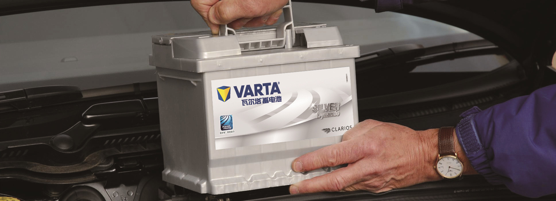 Person Installing Silver VARTA Battery Under Car Hood