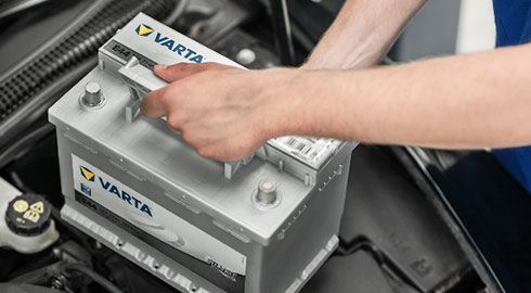 Person Installing VARTA Battery Under Car Hood
